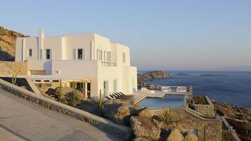 Un edificio moderno e bianco con piscina e vista sul mare.