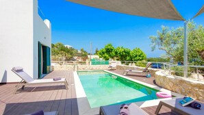 Zona de piscina amb gandules i una paret de pedra.