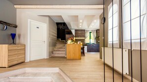 Un interior modern amb una escala que condueix a un segon pis, un escriptori de fusta i una zona de cuina.