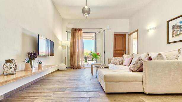 A modern living room with a sofa, a coffee table, and a TV mounted on the wall. - Villa Agricola with private swimming pool (Zakynthos)