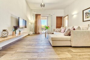 A modern living room with a sofa, a coffee table, and a TV mounted on the wall. - Villa Agricola with private swimming pool (Zakynthos)