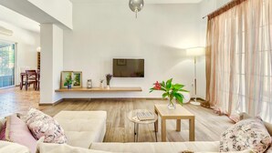 A spacious living room with a large flat-screen TV mounted on the wall, a wooden coffee table, and a sofa with floral cushions. - Villa Agricola with private swimming pool (Zakynthos)