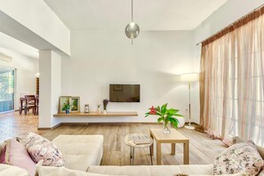 A spacious living room with a large flat-screen TV mounted on the wall, a wooden coffee table, and a sofa with floral cushions. - Villa Agricola with private swimming pool (Zakynthos)