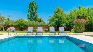 A rectangular swimming pool with clear blue water, surrounded by a wooden deck. There are four lounge chairs aligned along the pool's edge. - Villa Agricola with private swimming pool (Zakynthos)