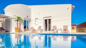 A modern white building with a pool, lounge chairs, and a potted plant. - Sky Beachfront Villa with private pool (Prinos)