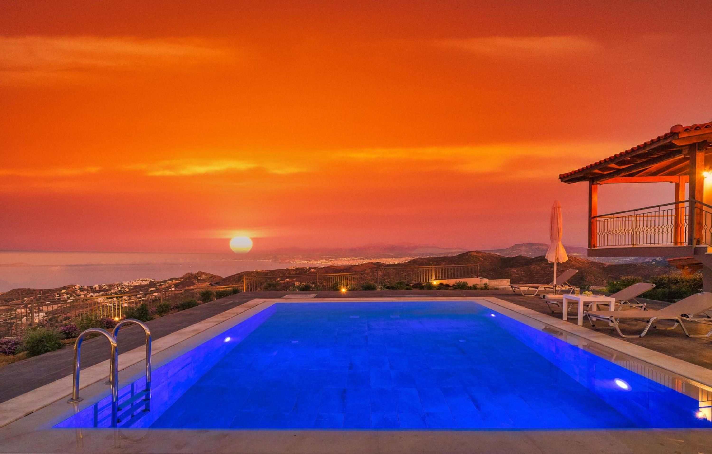 Ein Pool mit Blick auf den Sonnenuntergang, Liegestühle und ein überdachter Bereich mit Geländer.