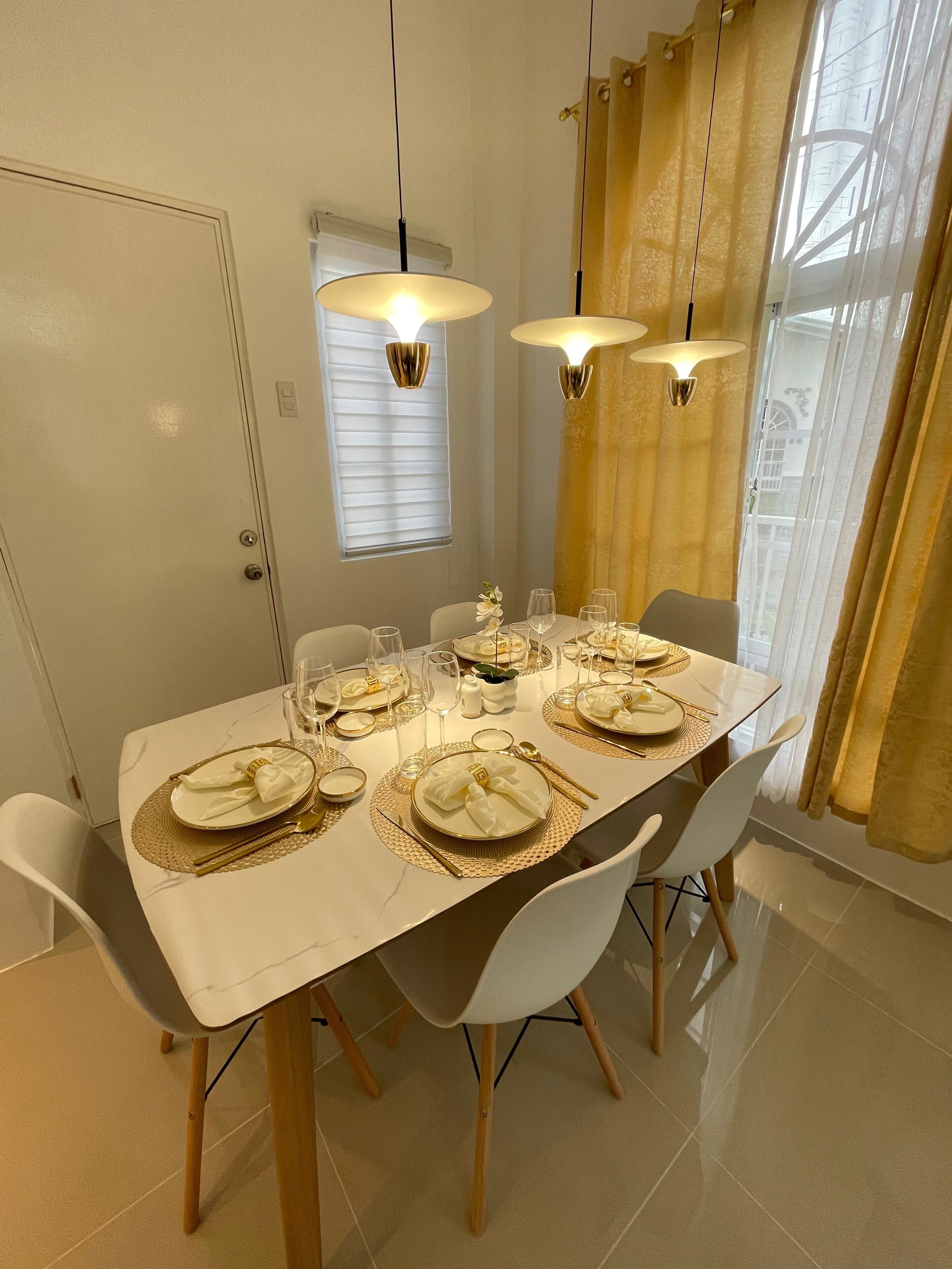 Un comedor con una mesa dispuesta para cuatro personas, incluyendo vajilla, copas y cubiertos.