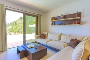 A modern living room with a sofa, coffee table, and decorative shelves. - Vista Mare Assinia in Kentroma (Kentroma)