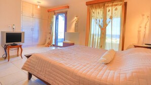 Een slaapkamer met een bed, een televisie, een kledingkast en een raam met gordijnen.