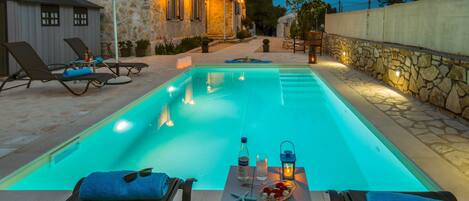 A swimming pool with lounge chairs and a table with amenities.