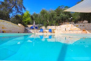 Ein Pool mit blauem Wasser, umgeben von Steinmauern und blauen Stühlen.