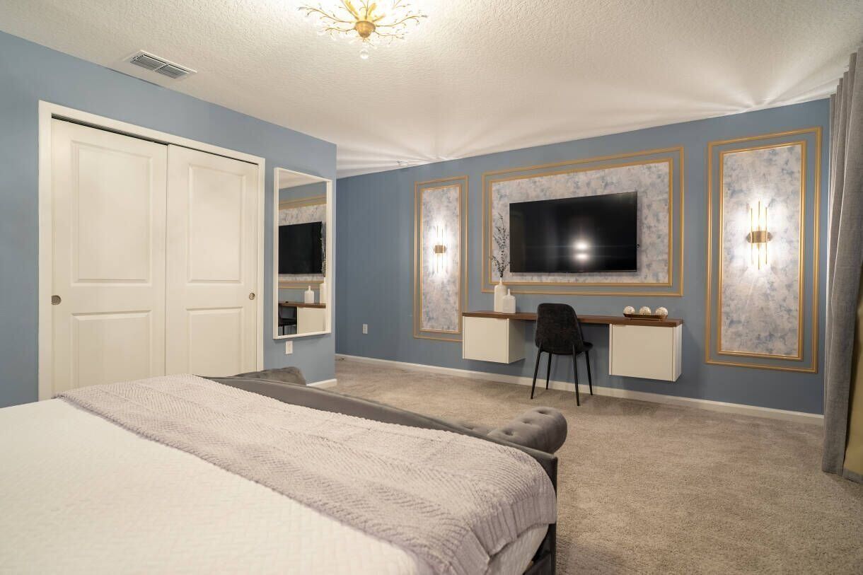 Una camera da letto con un letto, una scrivania, una sedia, una televisione e un armadio.