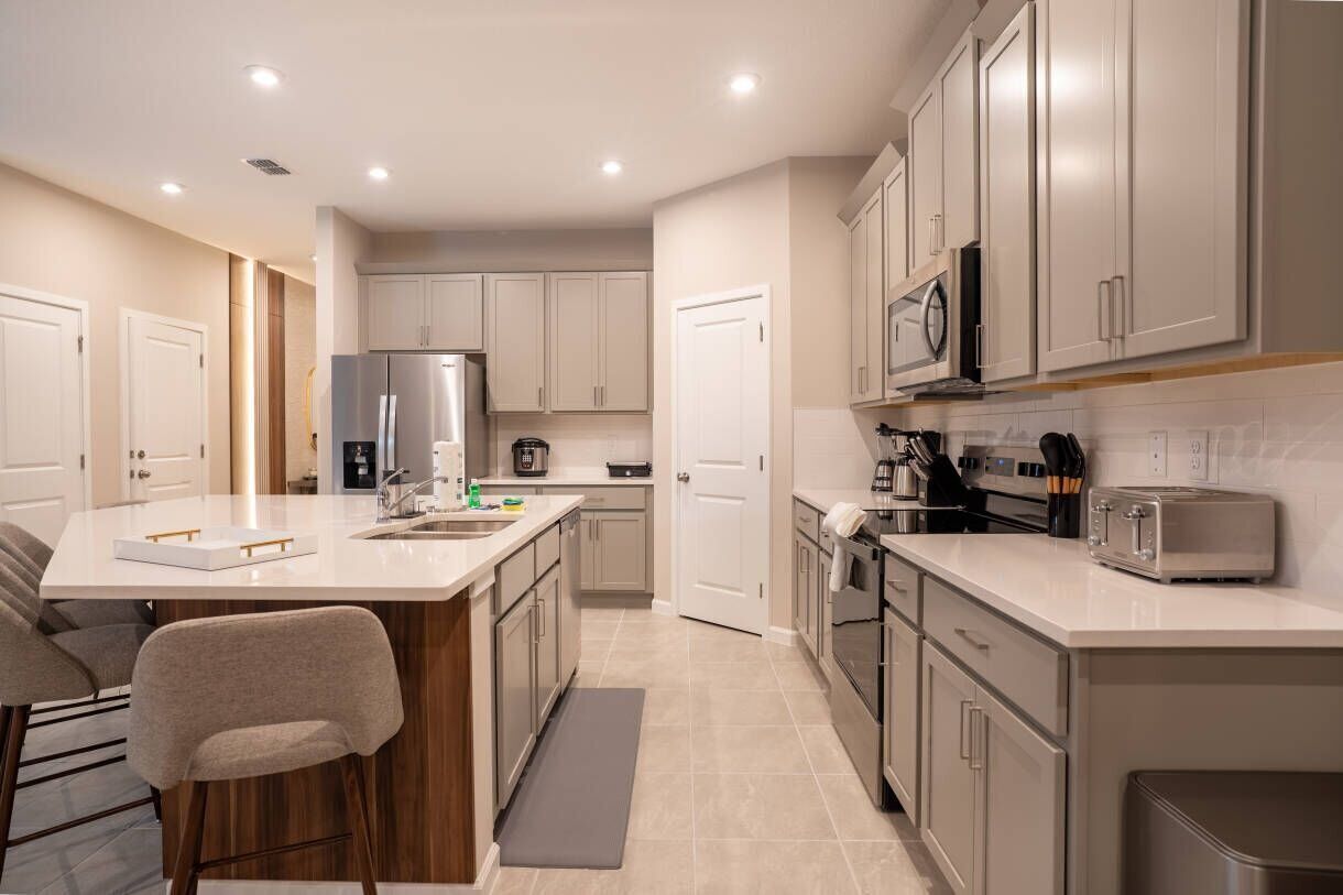 A modern kitchen with a central island, stainless steel appliances, and a walk-in pantry.