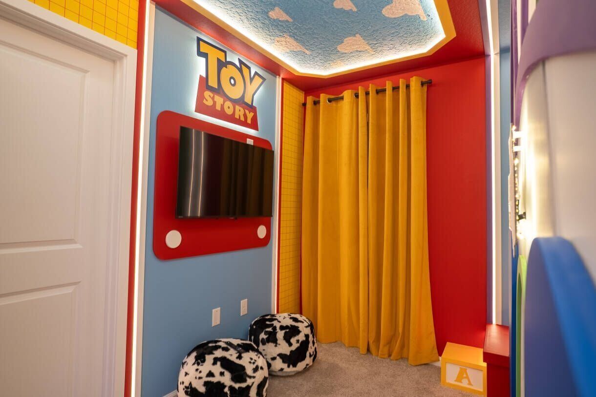 A room with a Toy Story-themed door, a yellow curtain, and two cow-patterned ottomans.