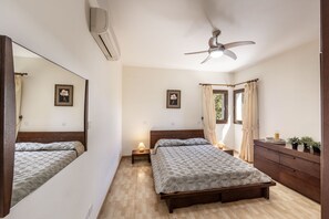 A bedroom with a bed, bedside tables, a ceiling fan, a dresser, and a window with curtains. - Villa Tsikkos Tria in Argaka (Argaka)