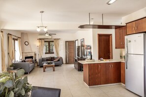A modern kitchen with wooden cabinets, a built-in island, and a refrigerator. - Villa Tsikkos Tria in Argaka (Argaka)