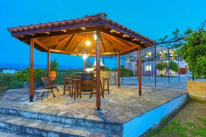An outdoor patio with a wooden pergola, stone flooring, and a seating area with chairs and a table. - Villa Athina Finiki in Latchi (Latchi)