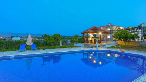 Una piscina con lettini e un gazebo.