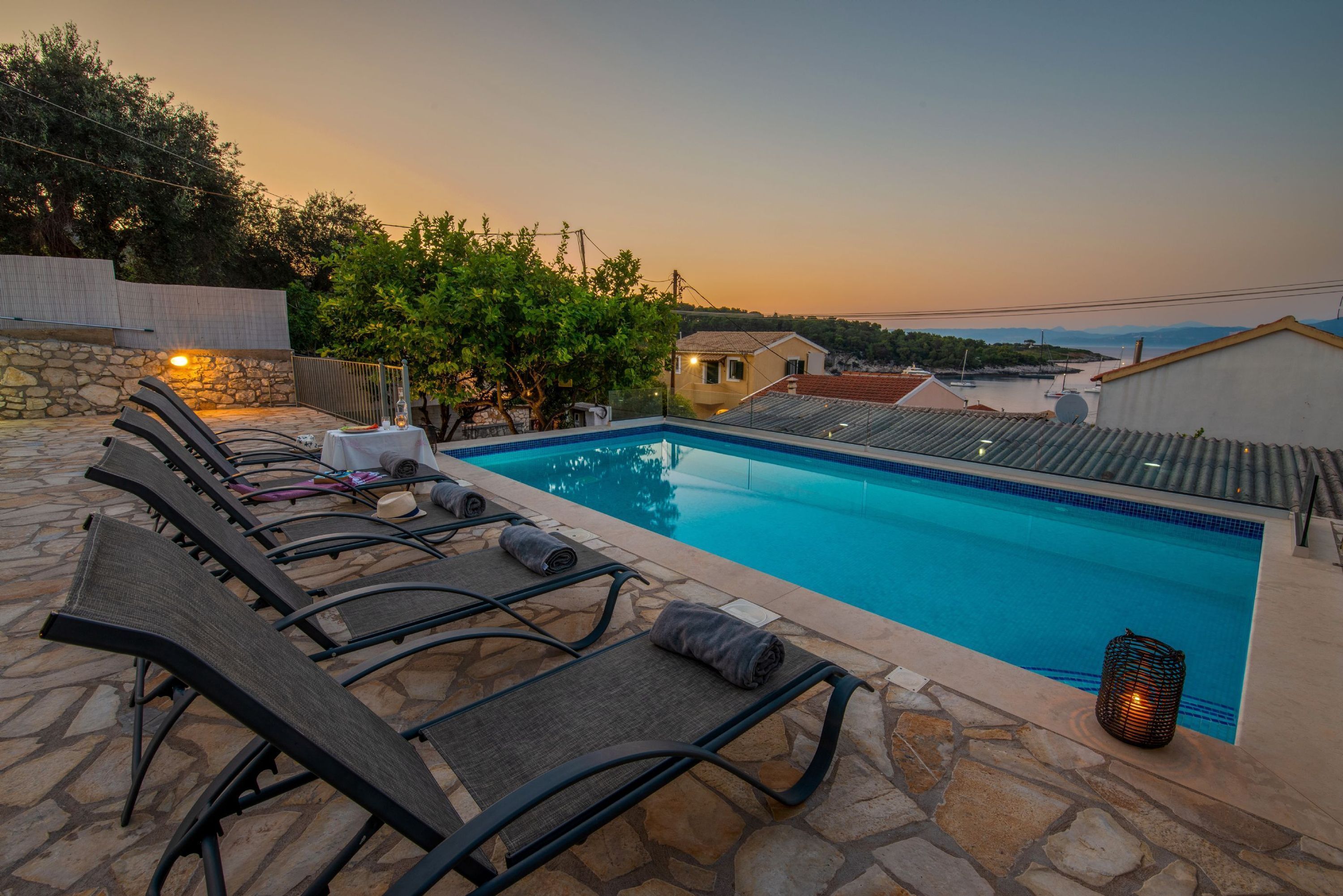 A swimming pool with lounge chairs and a stone-tiled deck.
