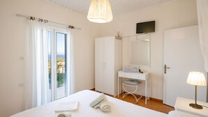 Ein Schlafzimmer mit Bett, Schreibtisch, Stuhl, Kleiderschrank, Fernseher und einem Balkon mit Blick.
