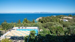 Ein Poolbereich mit Liegestühlen und Blick aufs Meer.