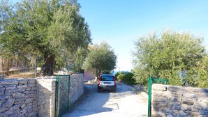 A stone-walled driveway leading to a parked car. - Antigoni Villa Ena in Longos (Longos)