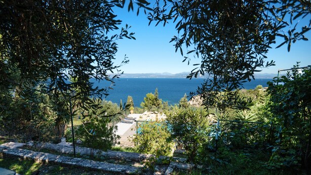 A view of a coastal area with a stone pathway leading to a seating area. - Antigoni Villa Ena in Longos (Longos)