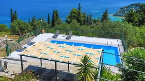 A pool area with lounge chairs and a view of the sea. - Antigoni Villa Ena in Longos (Longos)