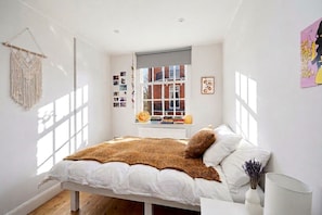 A bedroom with a bed, a window, and a wall with pictures. - [Superhost] 12 mins walk to Buckingham Palace & Big Ben - Cozy 2BR Family Rental (London)