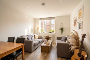 A modern living room with a dining table, sofas, a coffee table, and a guitar. - [Superhost] 12 mins walk to Buckingham Palace & Big Ben - Cozy 2BR Family Rental (London)