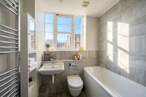 A modern bathroom with a window, a sink, a toilet, and a bathtub. - [Superhost] 12 mins walk to Buckingham Palace & Big Ben - Cozy 2BR Family Rental (London)