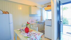 A compact kitchen with a refrigerator, a sink, and a dining area with a table. - Antigoni Villa Tria in Longos (Longos)