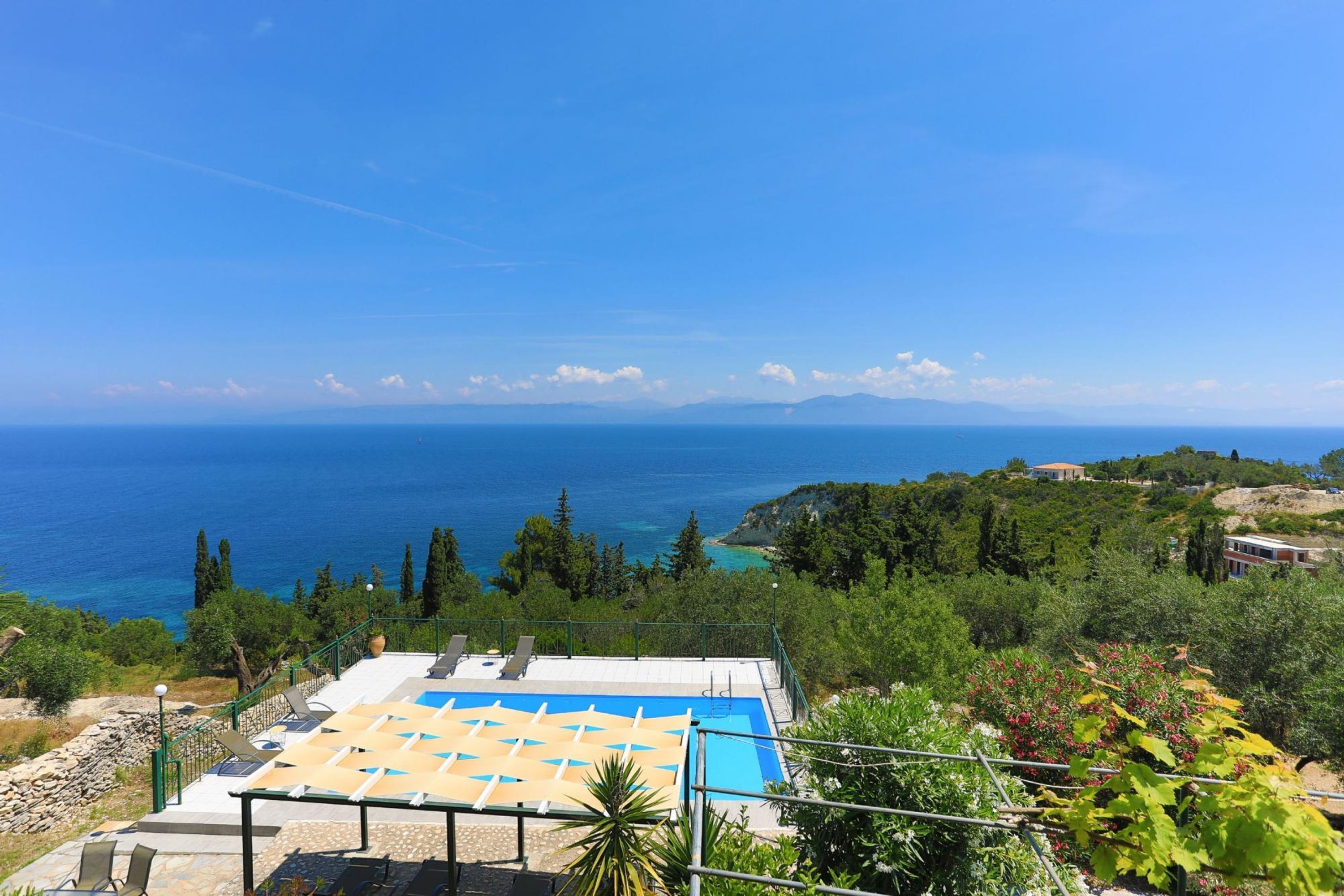 Une piscine sur le toit offrant une vue dégagée sur la mer et les montagnes lointaines.