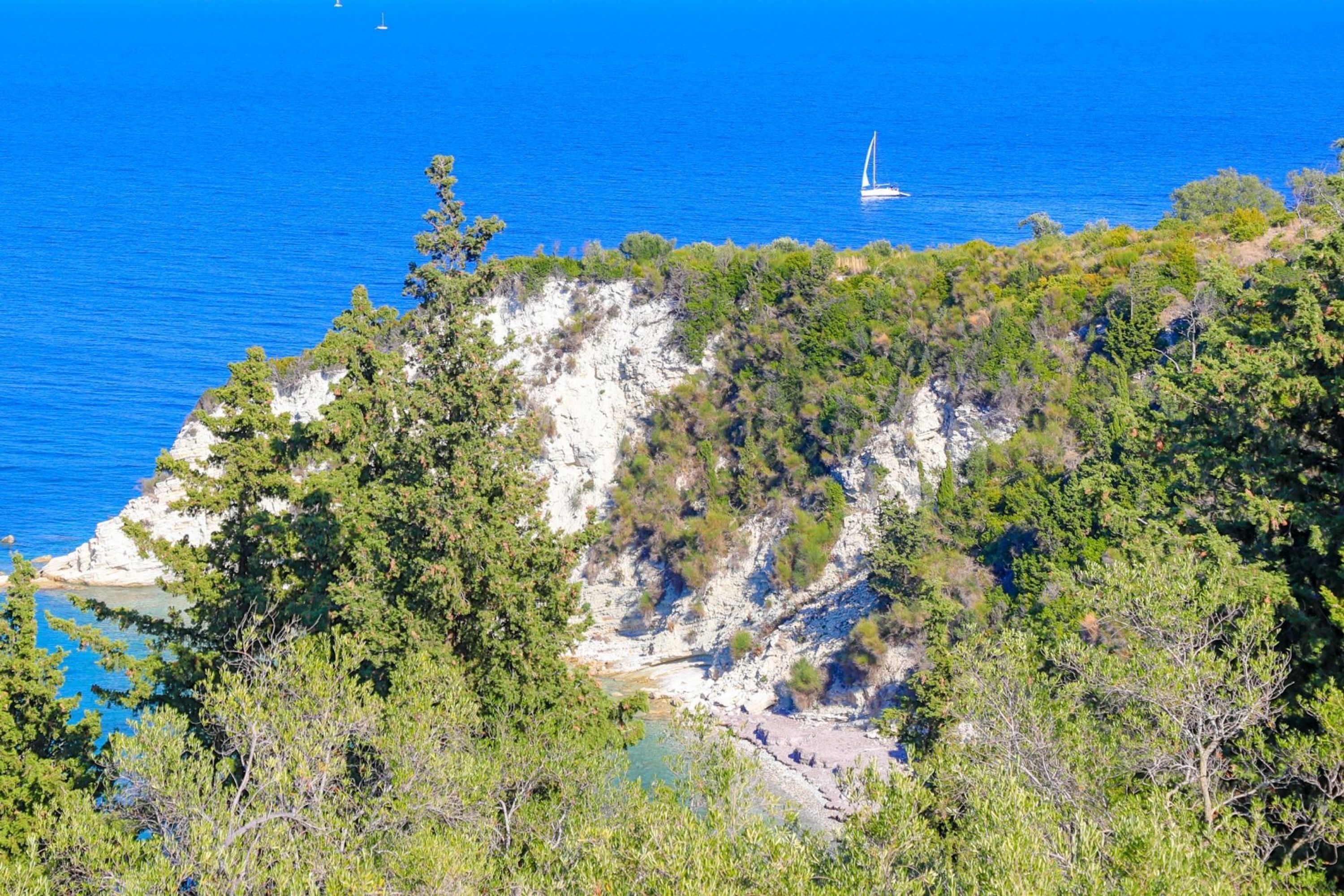 Un paysage côtier caractérisé par des falaises rocheuses, une végétation luxuriante et une mer d’un bleu limpide.