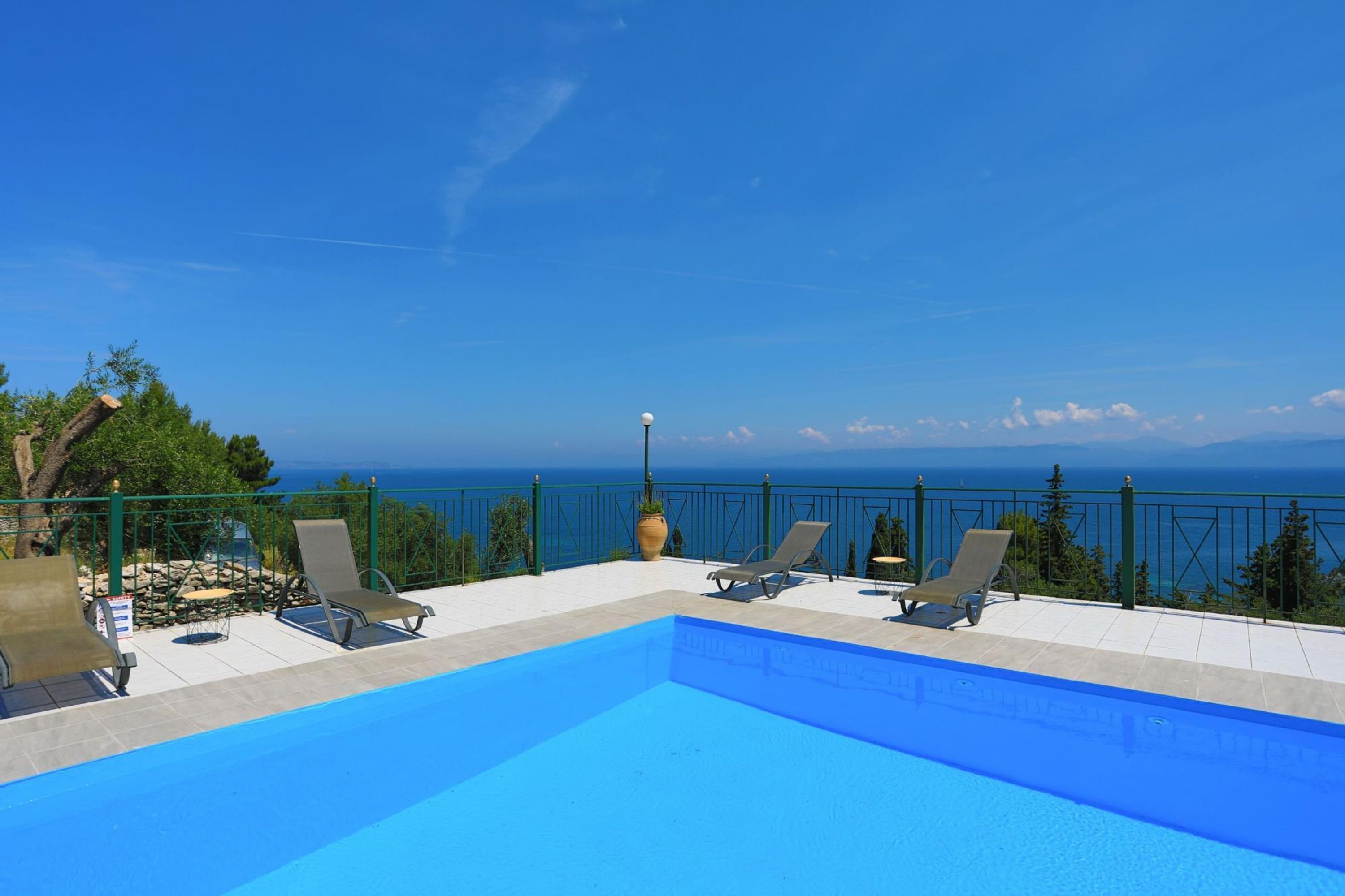 Une piscine avec des chaises longues et vue sur la mer.