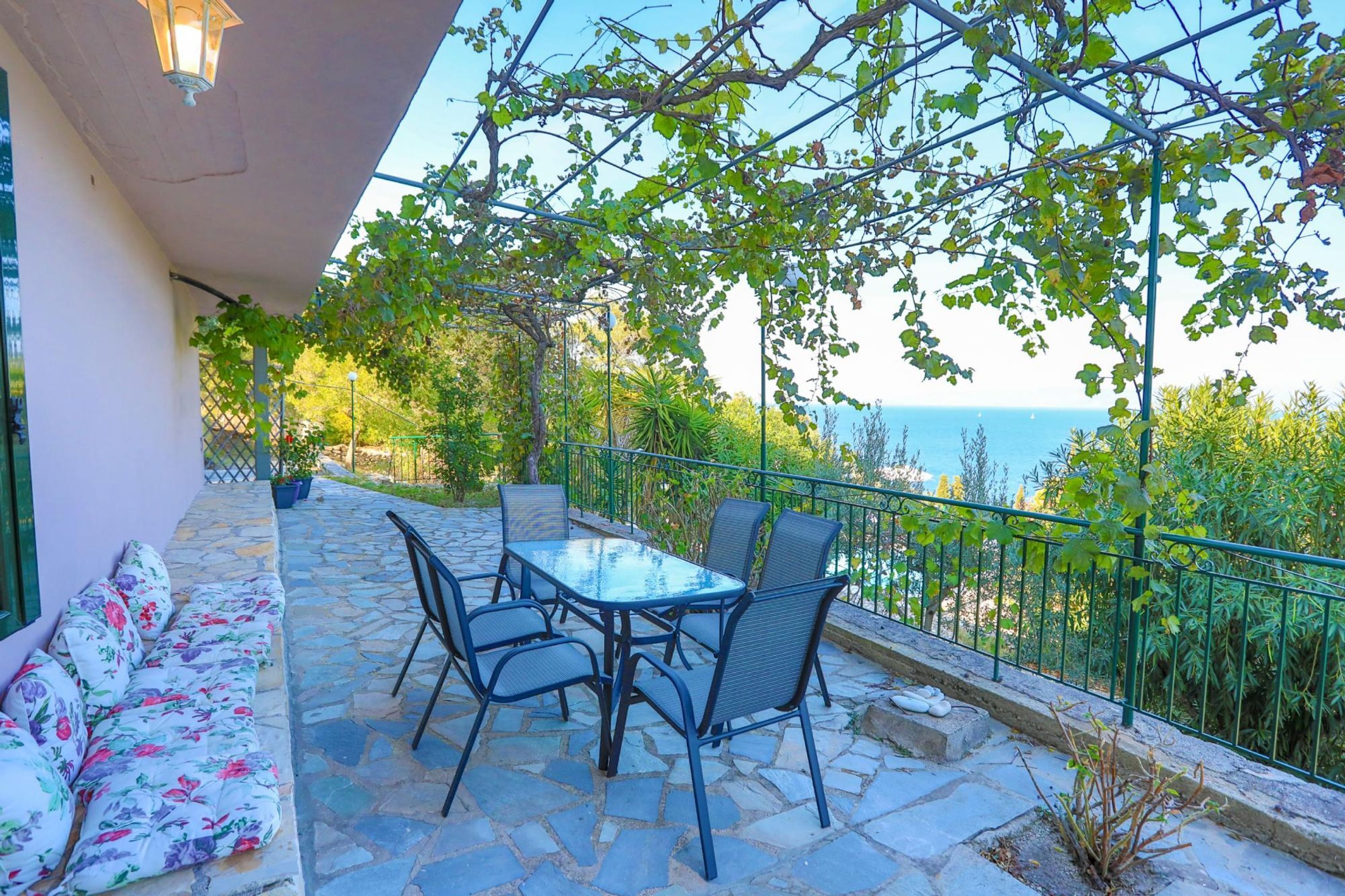 Eine Terrasse mit Tisch, Stühlen und einer Sitzecke, mit Blick auf das Meer.