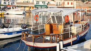 A small boat docked at a marina with a cabin, life preserver, and wooden deck. - Villa Sevi in Loggos (Paxi)
