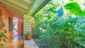 A covered outdoor area with a stone pathway, potted plants, and a variety of greenery. - Villa Calypso in Nisaki (Nisaki)