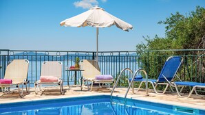 A pool area with lounge chairs and an umbrella. - Villa Calypso in Nisaki (Nisaki)