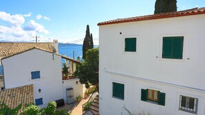 Un bâtiment situé sur la côte, doté d’un toit recouvert de tuiles, de murs blancs et de volets verts.