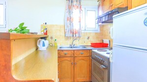 Une cuisine de taille réduite, dotée de meubles de rangement en bois, d’un évier, d’une cuisinière et d’un réfrigérateur.