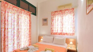 Een hotelkamer met twee bedden, bloemen gordijnen, een schilderij aan de muur en een bedlampje.