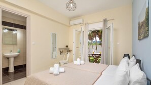 A hotel room with a bed, a bathroom with a sink, and a view of the outdoors. - Villa Paradiso in Agnos (Roda)