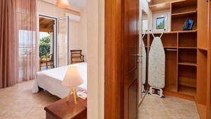 A hotel room with a bed, a desk with a lamp, a wardrobe, and an ironing station. - Sunset House in Sidari (Corfu)