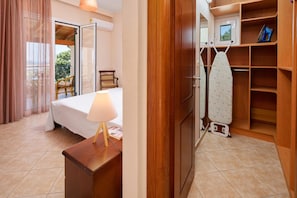 A hotel room with a bed, a desk with a lamp, a wardrobe, and an ironing station. - Sunset House in Sidari (Corfu)