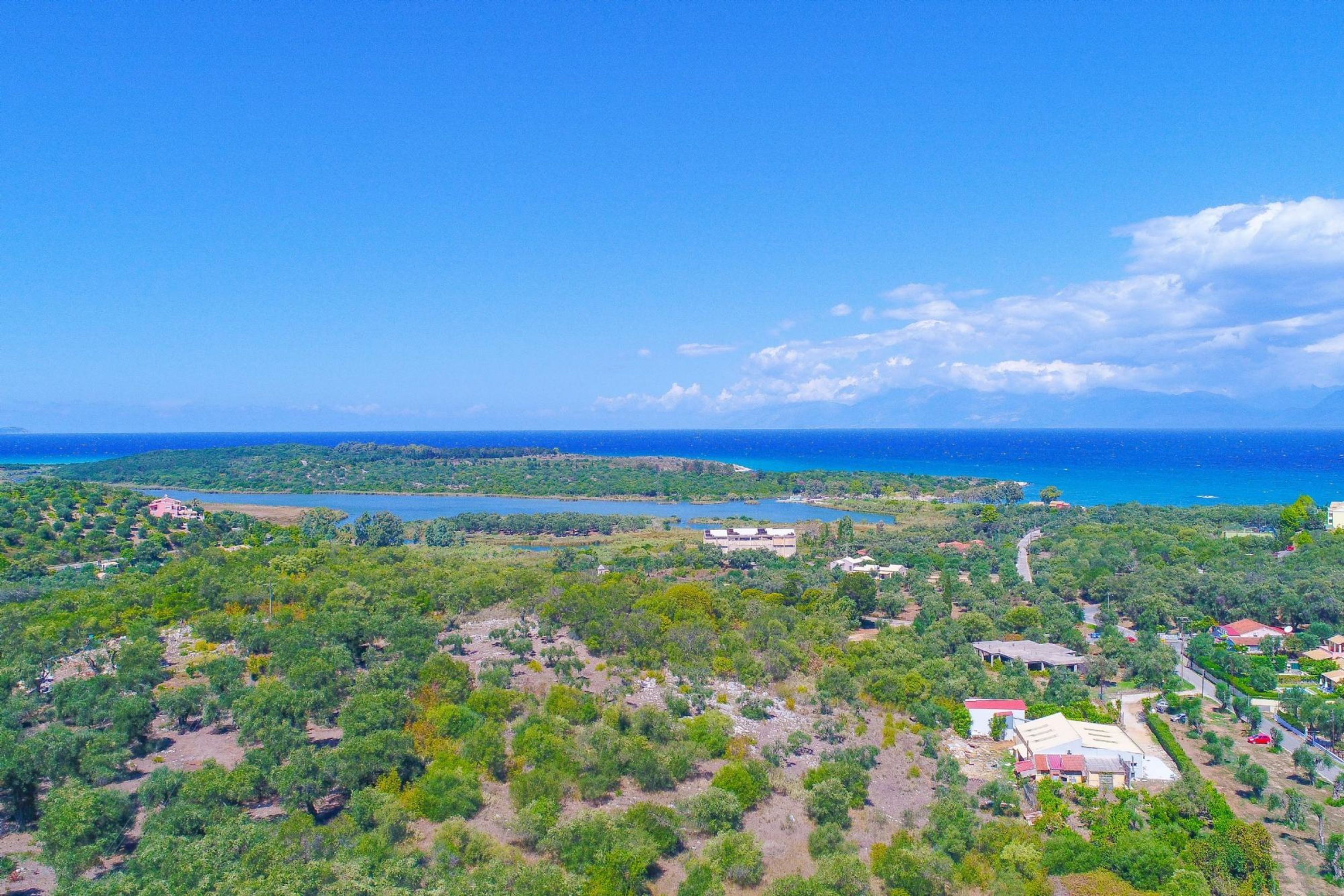 Une vue aérienne d’une zone côtière parsemée de bâtiments, avec un lac et un ciel bleu dégagé.
