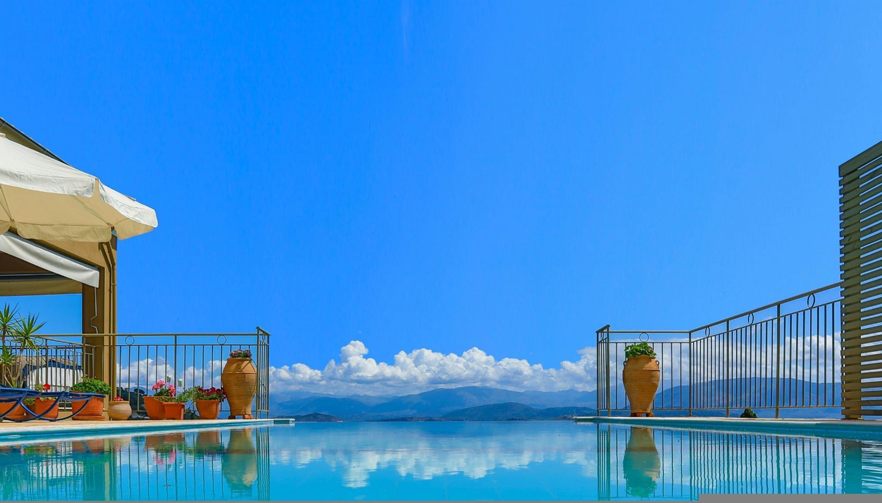 Ein Pool mit klarem, blauem Wasser, umgeben von Metallgeländern und Kübelpflanzen.
