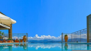 Ein Pool mit klarem, blauem Wasser, umgeben von Metallgeländern und Kübelpflanzen.