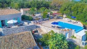 A villa with a swimming pool, stone walls, outdoor seating, and a view of the surrounding hills. - Villa Helona in Lithiasmenos (Lithiasmenos)