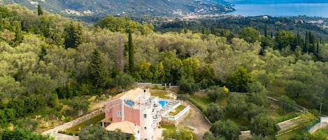 Une villa avec piscine, entourée d’une végétation luxuriante et avec des montagnes en toile de fond.